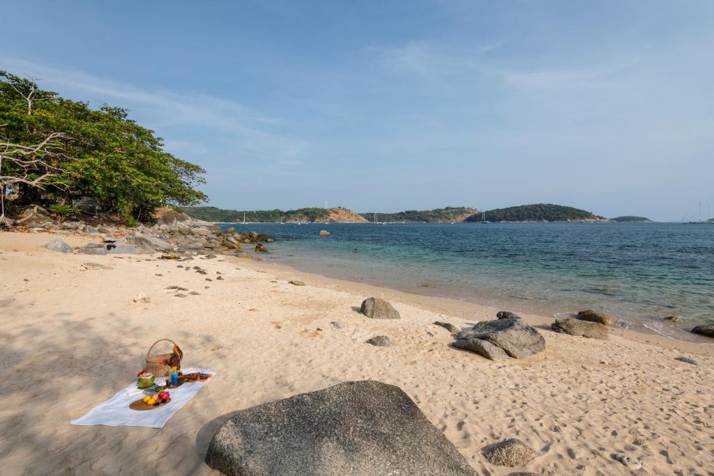 奈汉海滩Baan Krating Phuket Resort -SHA Plus的沙滩上有岩石和一篮子