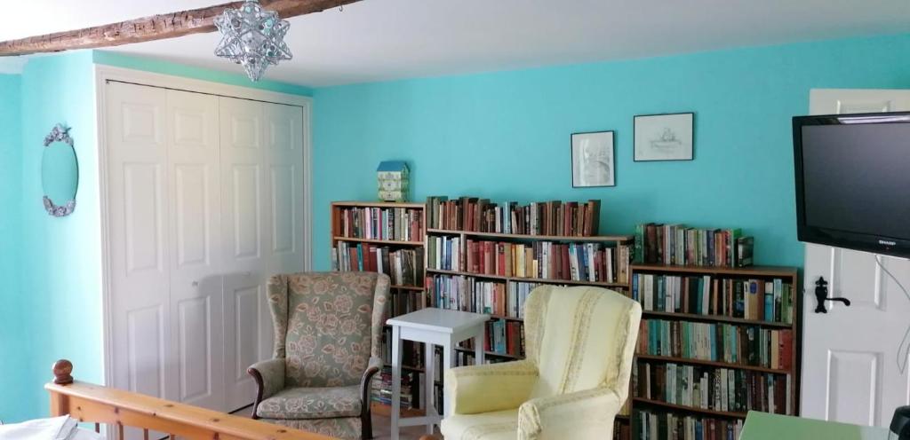 卡莱尔Newby Cross的一间房间,配有两把椅子、一台电视和书架