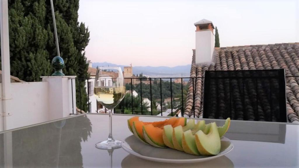 格拉纳达卡门德拉斯坎帕纳斯度假屋的桌上的水果和一杯葡萄酒