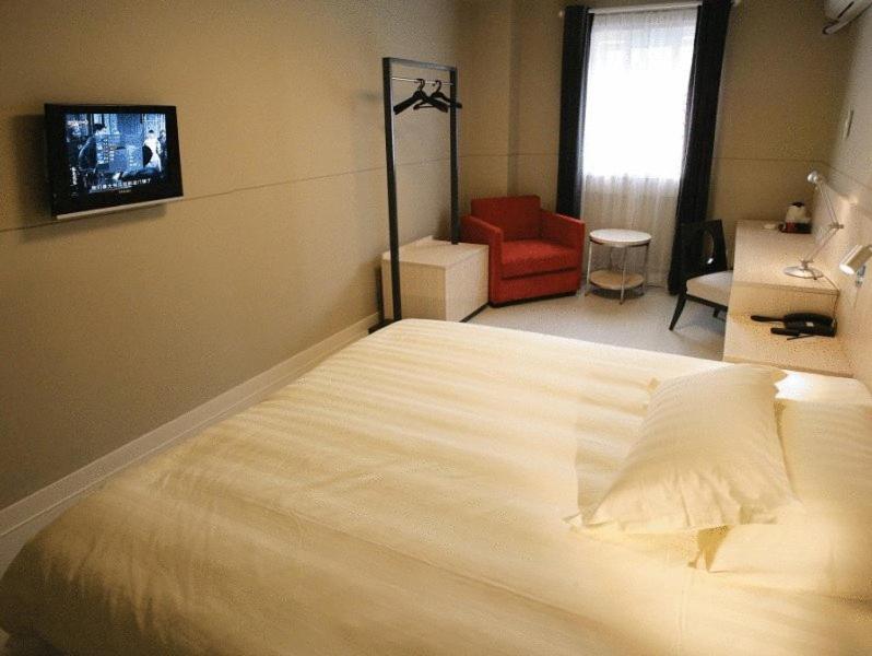 长沙锦江之星长沙东风路店的卧室配有一张白色大床和红色椅子