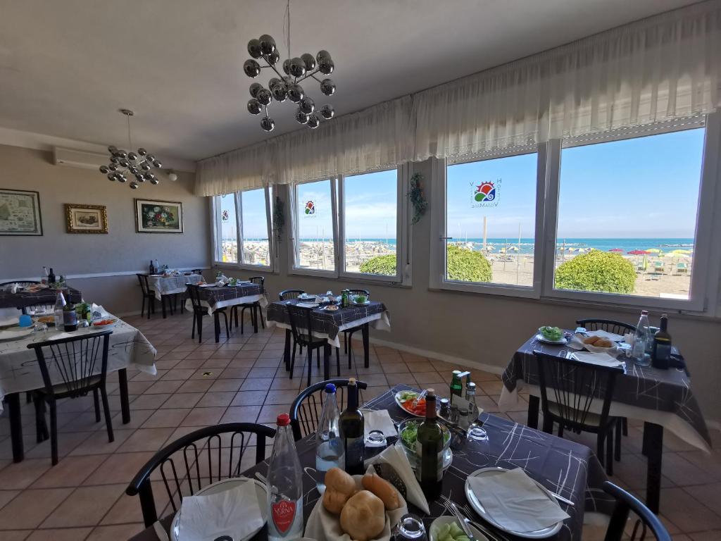 里米尼Hotel VistaMare Viserba的一间带桌椅的海景餐厅