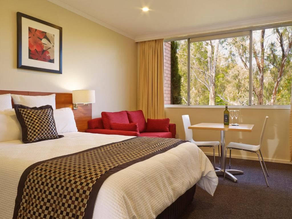 旺加拉塔Parkview Motor Inn and Apartments的酒店客房设有床、桌子和窗户。