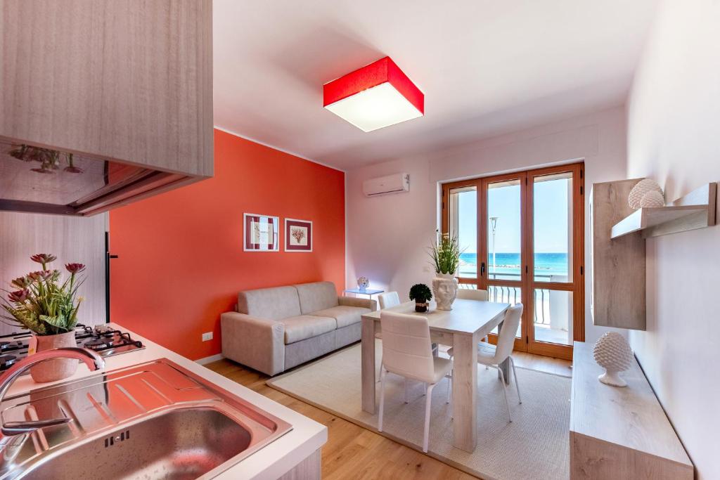 奥特朗托Appartamenti fronte mare Otranto的一间厨房和带橙色墙壁及桌子的客厅