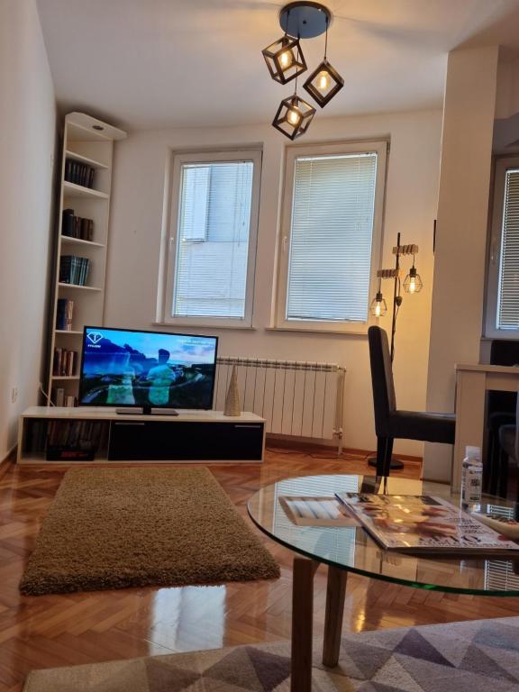 弗拉涅Apartman Veselinovic Free PARKING的一间带电视和玻璃桌的客厅