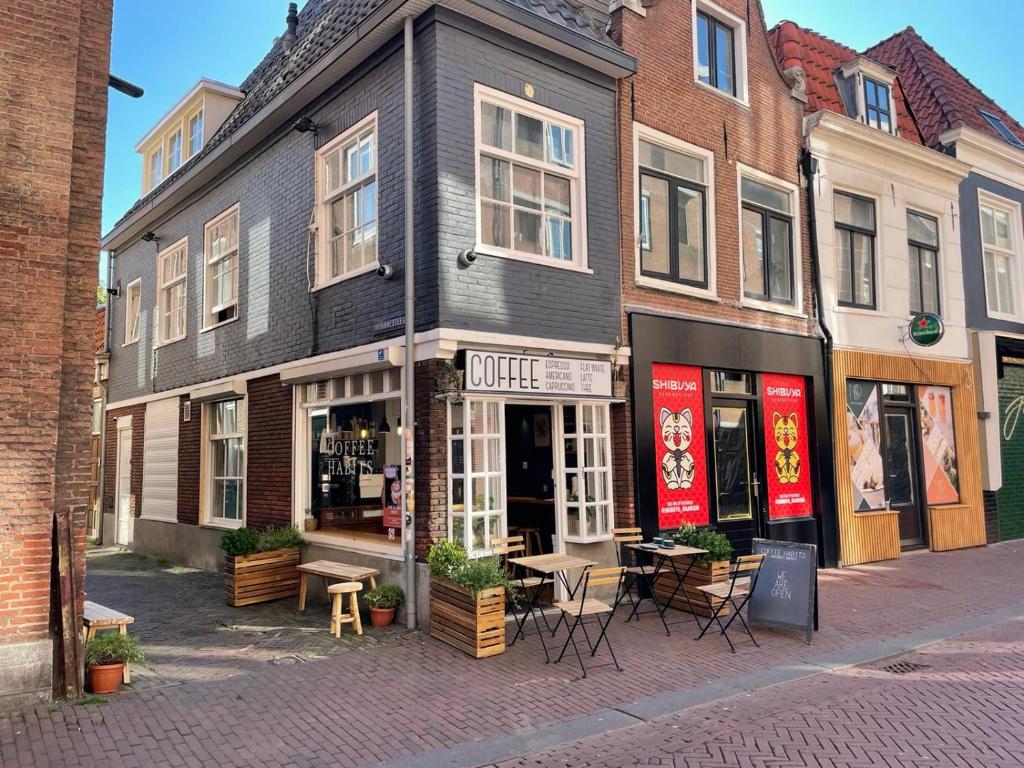 哈莱姆Tiny Private City Rooms Haarlem的城市街道上的一座建筑,配有桌椅
