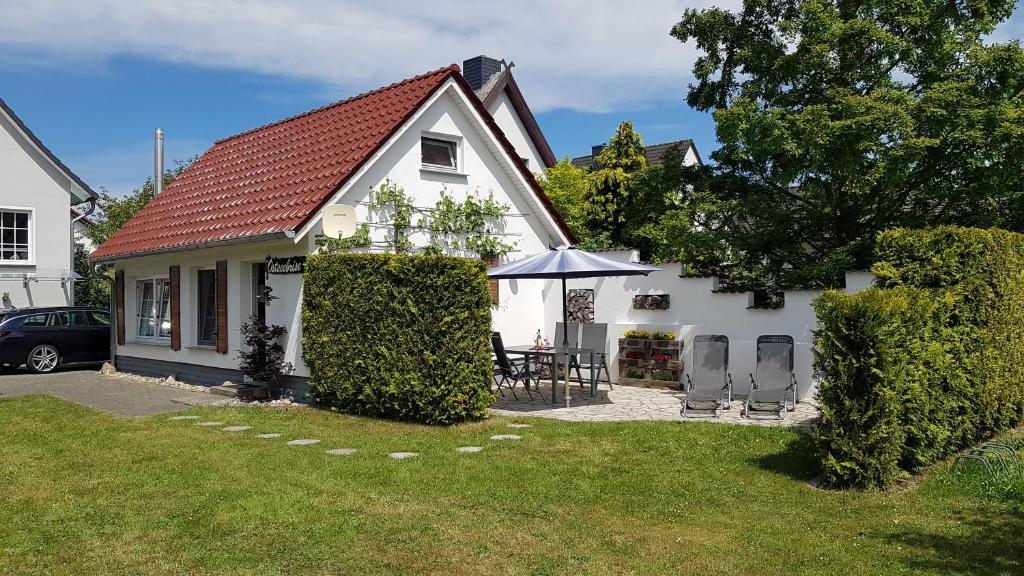 卡尔斯哈根Ferienhaus Ostseebrise Insel Usedom的白色的房子,配有桌子和雨伞