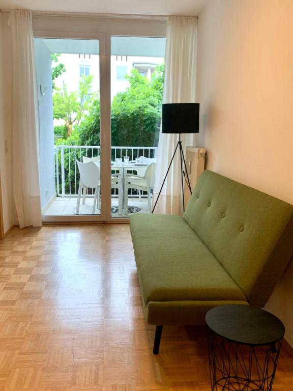 克拉根福Appartement Lilienthal的客厅设有绿色沙发和阳台。