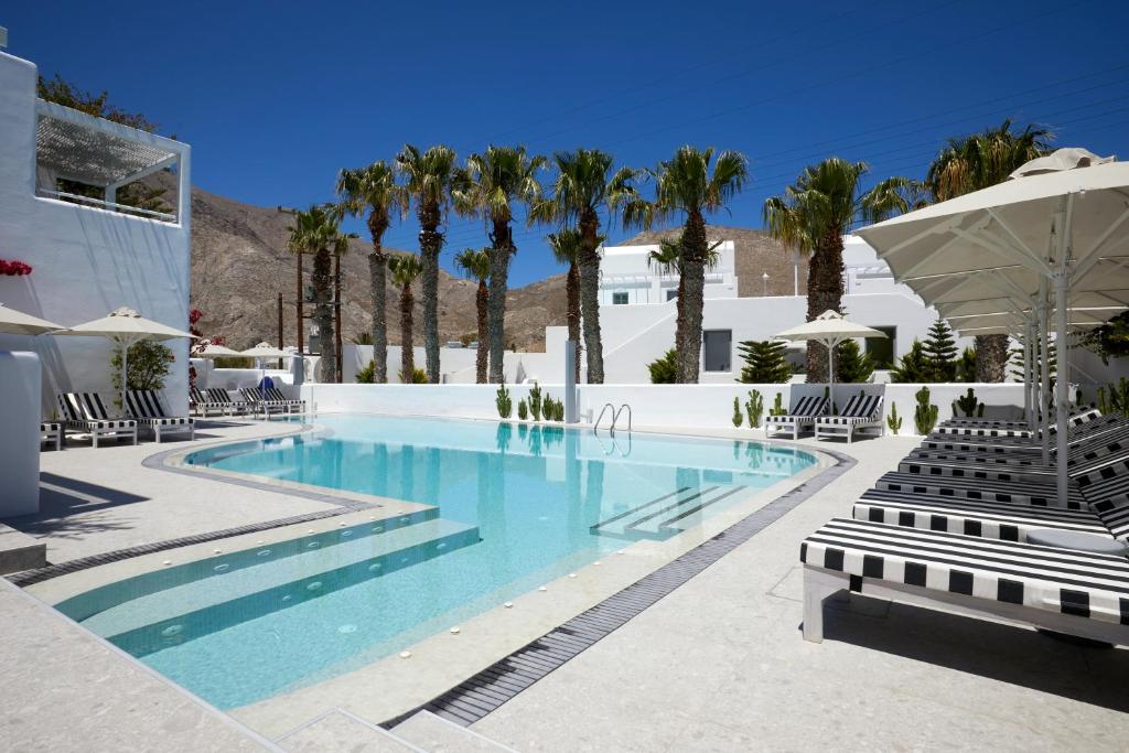 佩里萨Kouros Village Hotel - Adults Only的一个带椅子的游泳池,棕榈树