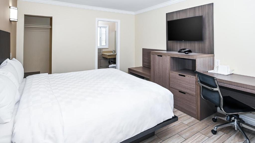 长滩Sea Rock Inn - Long Beach的酒店客房配有一张床、一张书桌和一台电脑