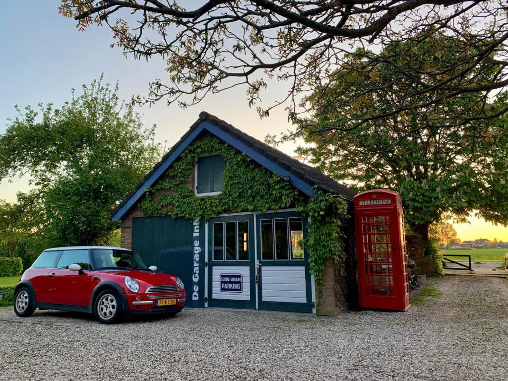 HankHoliday cottage de Garage Inn的一辆红色的汽车停在一个小房子前面,里面装有电话亭