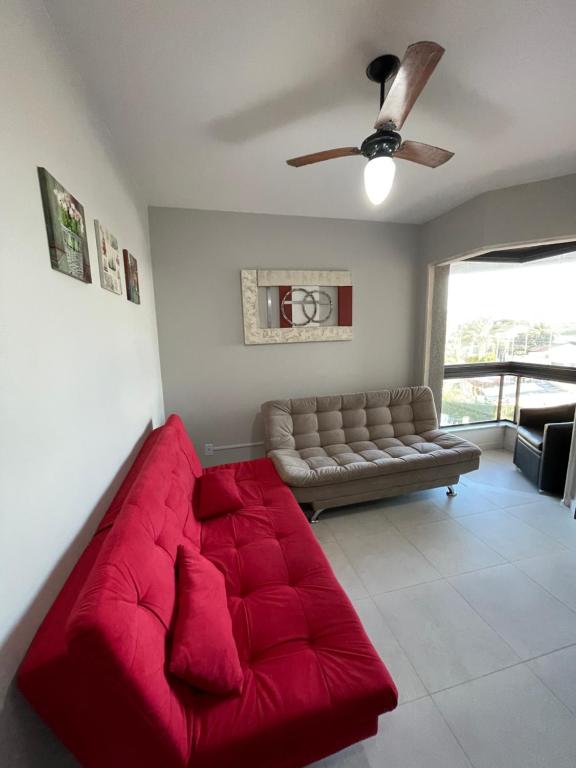 弗洛里亚诺波利斯Apartamento Florianópolis ponta das canas的客厅配有红色沙发,设有吊扇