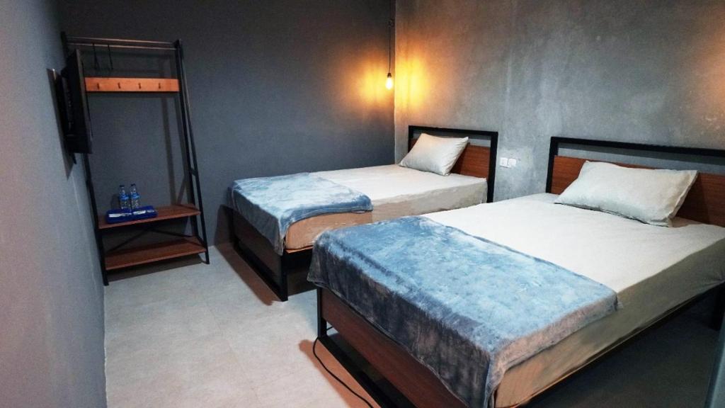 万隆Hostel 18 Pasangan Butuh Surat Nikah的酒店客房设有两张床和床头柜。