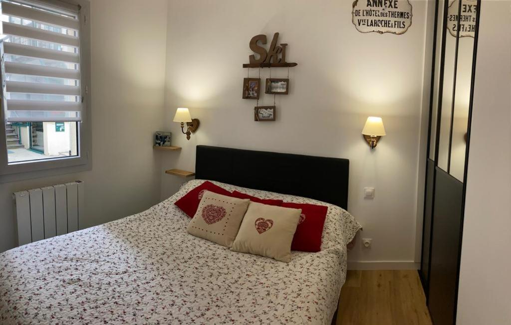 勒蒙多尔Appartement Les Amethystes 1的一间卧室配有一张带红色枕头的床和一扇窗户