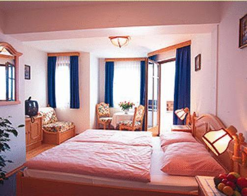 圣沃尔夫冈林奥特纳膳食公寓酒店的一间卧室配有一张带蓝色窗帘的大床