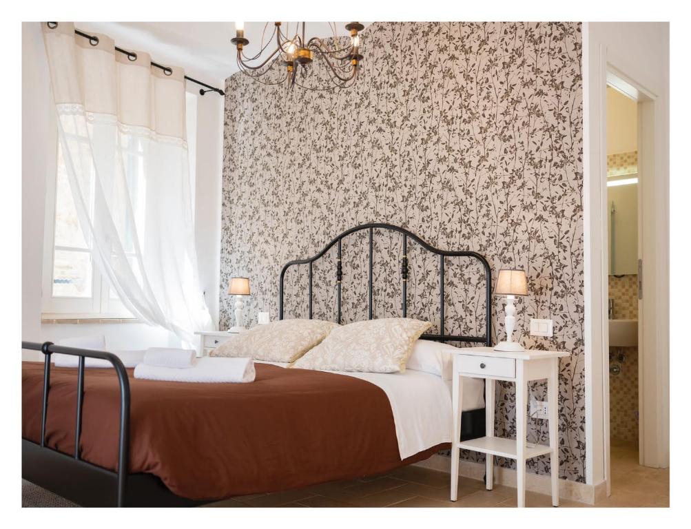 瓜尔多卡塔内奥RESIDENCE IL GROTTINO的一间卧室配有一张床和一张带花卉壁纸的墙壁