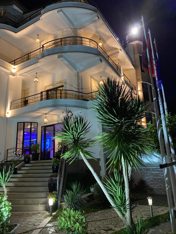 爱尔巴桑Garden Boutique Hotel的一座晚上有楼梯和棕榈树的建筑