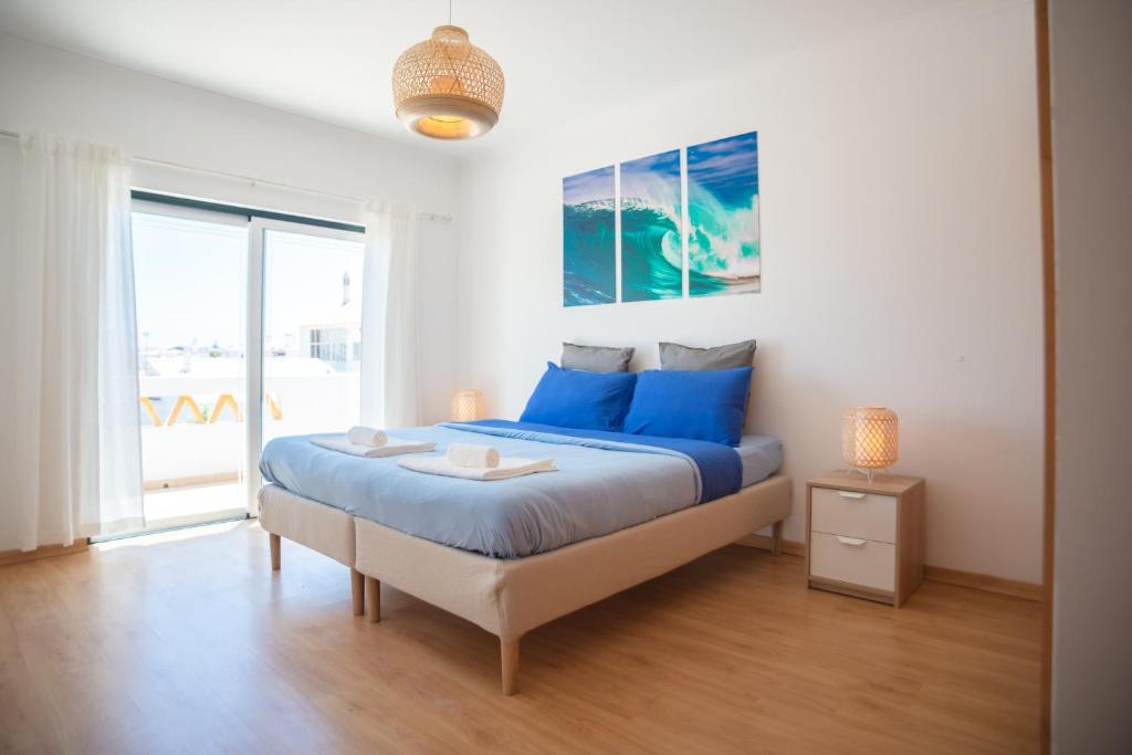萨格里什Kichershome的一间卧室配有一张带蓝色床单的床和一扇窗户。
