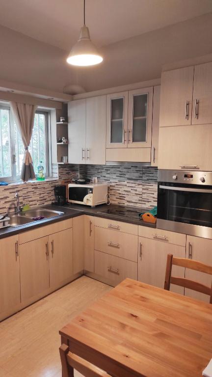 雅典Alimos Apartment的厨房配有白色橱柜和木桌