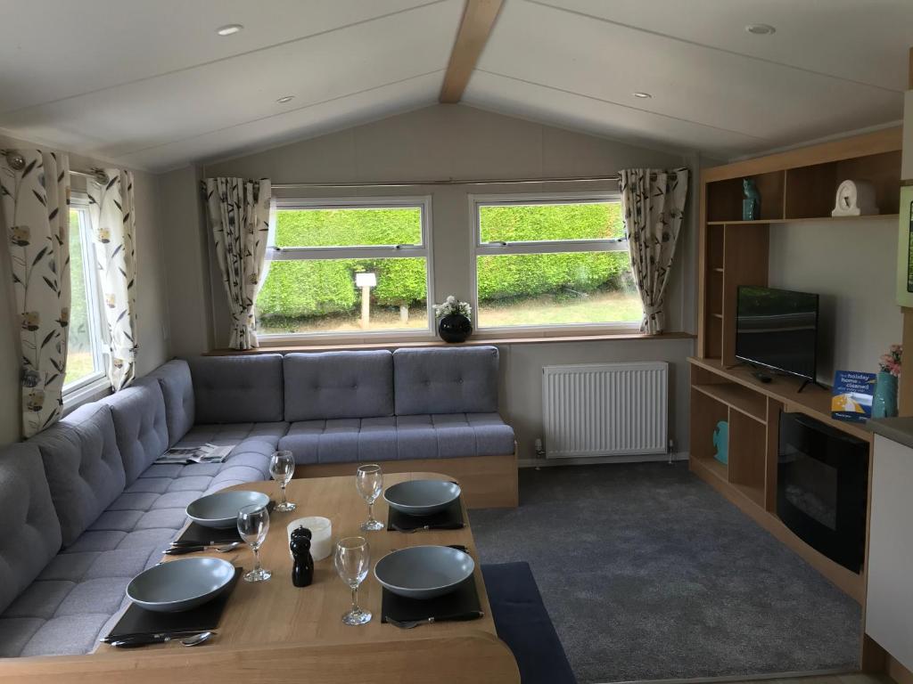 Newquay Bay ResortExclusive 3 Bedroom Caravan, Sleeps 8 People at Parkdean Newquay Holiday Park, Cornwall, UK的客厅配有沙发和桌子