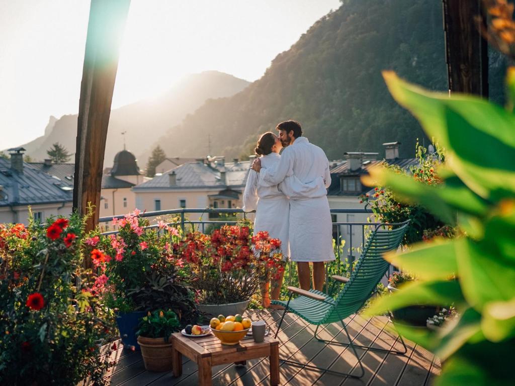 萨尔茨堡Boutique Hotel & Villa AUERSPERG的一对夫妇站在一个种着鲜花的阳台的顶端
