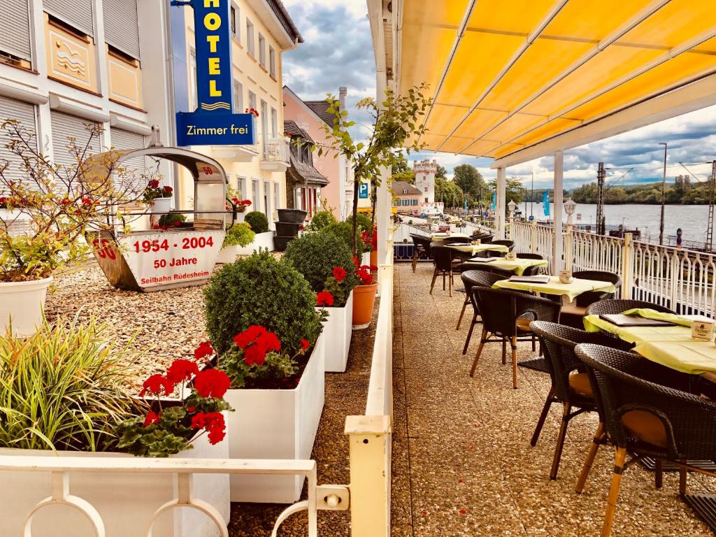 吕德斯海姆吕德斯海姆公园酒店的一个带桌椅和鲜花的餐厅庭院
