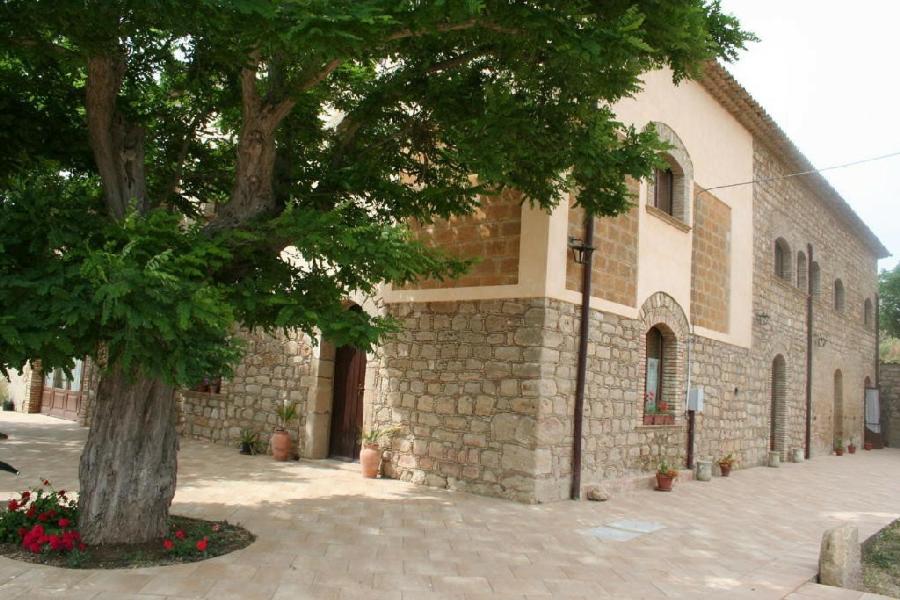 皮亚扎-阿尔梅里纳Agriturismo Camemi di Paternico Ettore Piazza Armerina (EN)的一座石头建筑,前面有一棵树