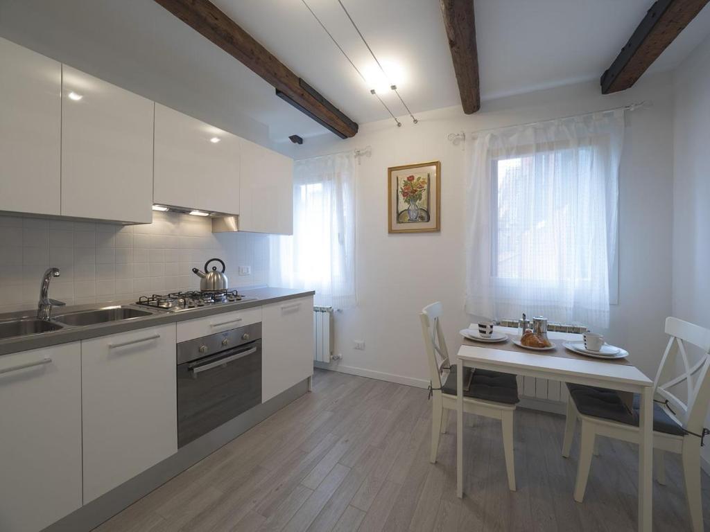 威尼斯SS吉奥瓦尼鲍罗公寓的厨房配有白色橱柜和桌椅