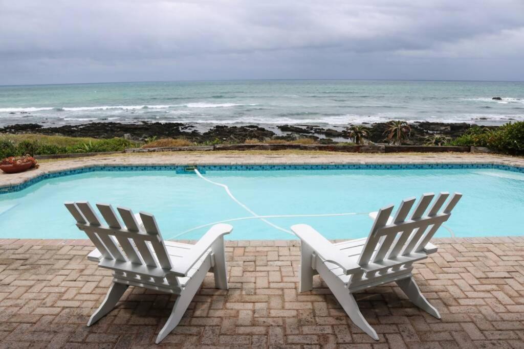 Kini BayOceans End - a home on the beach的两把椅子坐在一个海洋游泳池旁