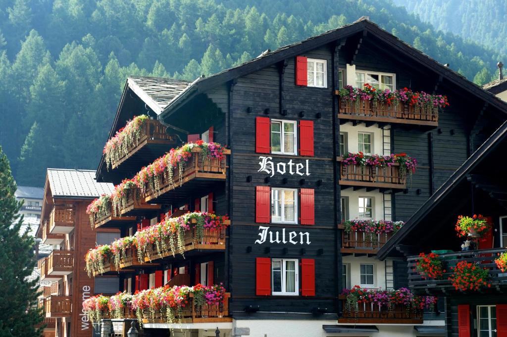 采尔马特Tradition Julen Hotel的黑色建筑,窗户上装有花盒