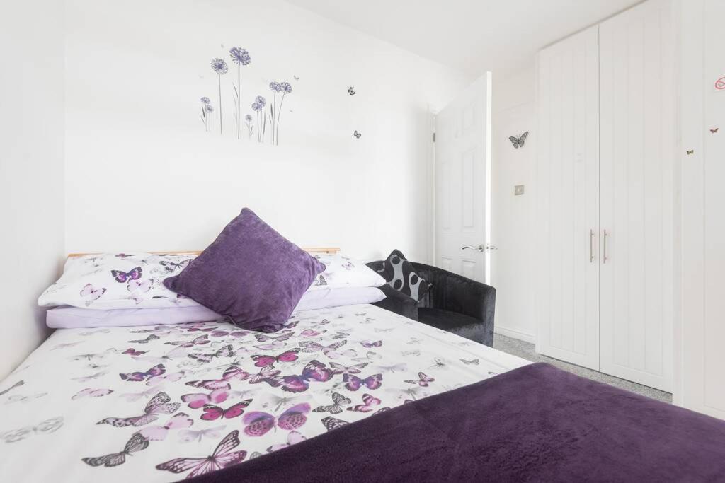 塞尔西Mayberry Lodge的一间卧室配有一张带紫色枕头和鲜花的床