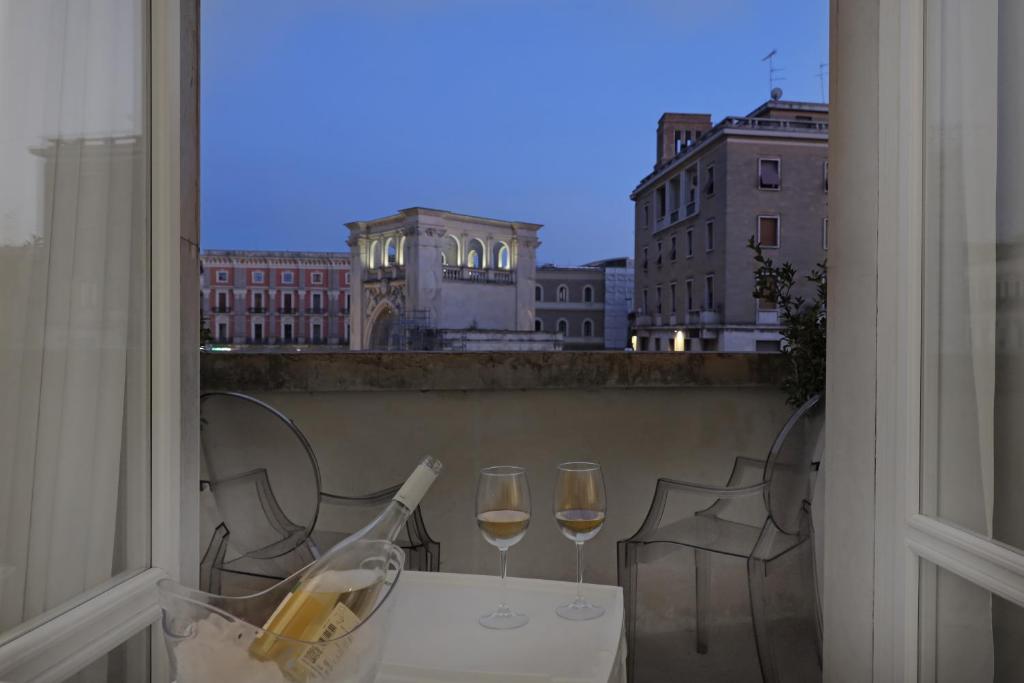 莱切Luxury House Lecce -Le mie 3 Suites-的阳台上的桌子和两杯葡萄酒