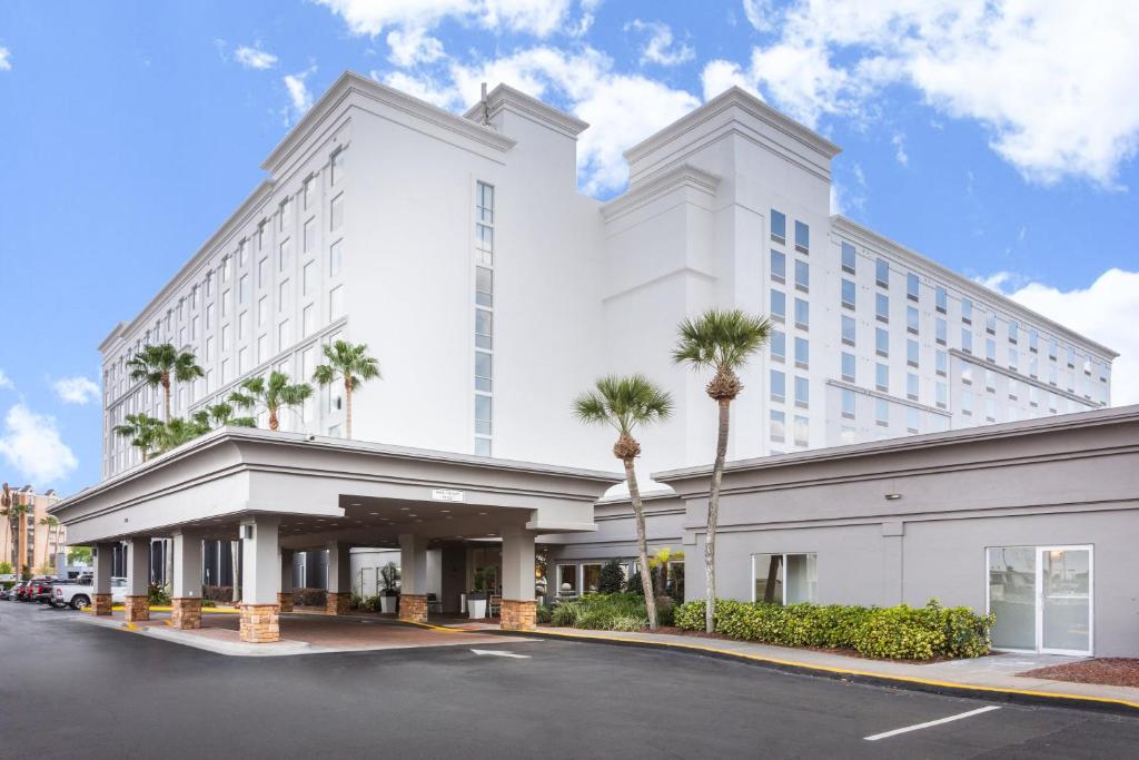 奥兰多Holiday Inn & Suites Across From Universal Orlando, an IHG Hotel的一座白色的大建筑,前面有棕榈树