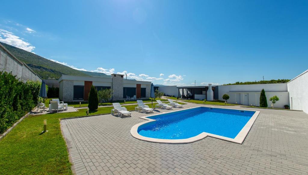 莫斯塔尔Luxury Villa in Mostar的一座带椅子的庭院和一座建筑中的游泳池