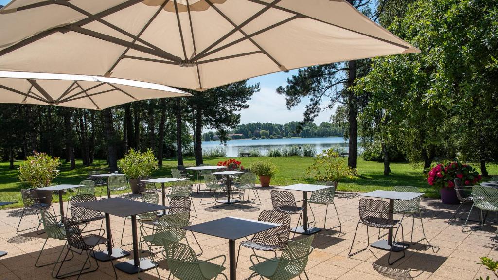 艾姆波茨卡佩尔Best Western Hotel du Lac Dunkerque- Restaurant ouvert 7/7 midi et soir的一组桌椅和遮阳伞