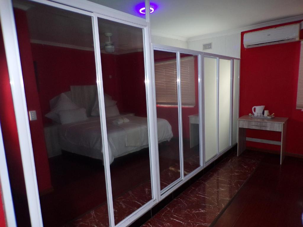 开普敦Khaya B&B Mandalay的一间设有卧室、一张床和玻璃墙的客房