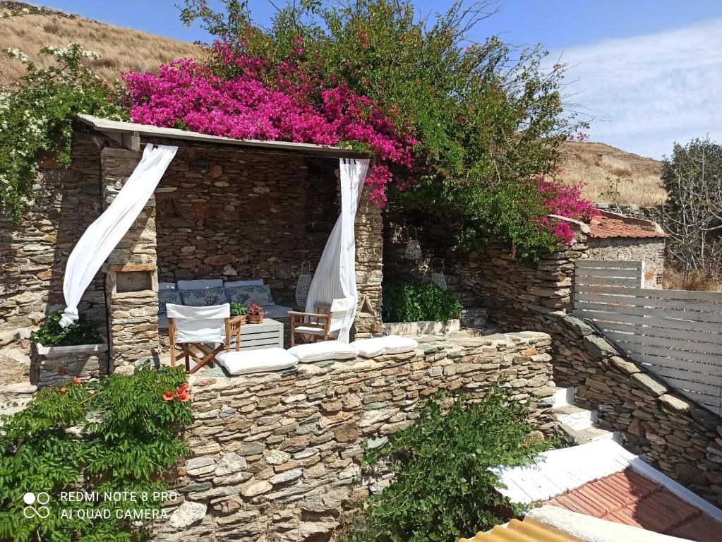 科里夏Hidesign Athens Traditional Stone House in Kea's Port的石墙,带椅子和鲜花的庭院