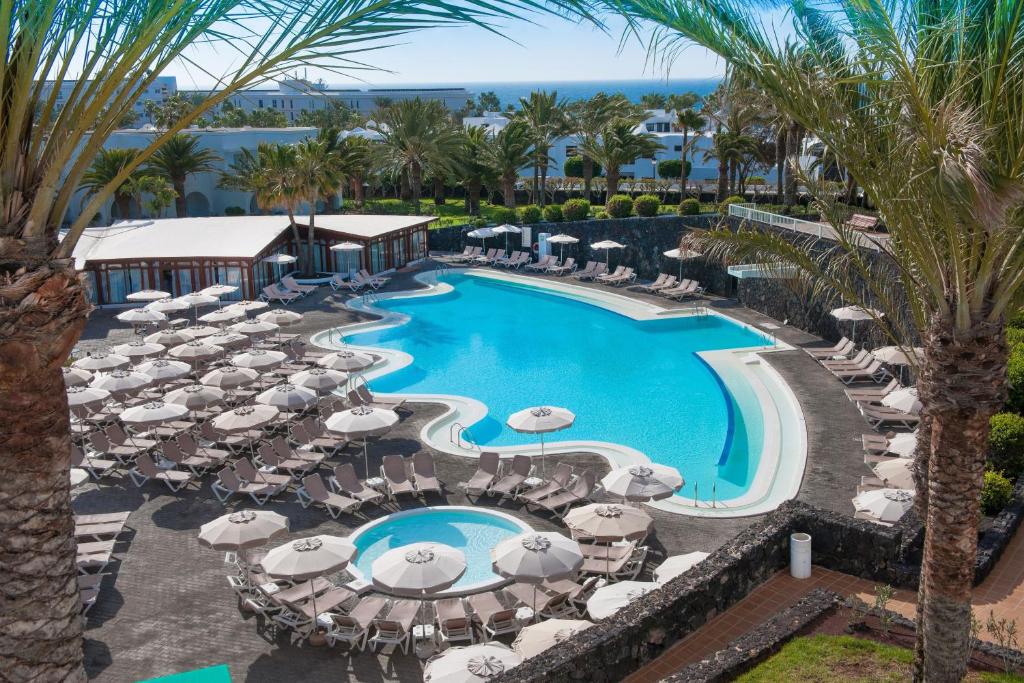 卡门港奥利维亚休闲酒店的享有带遮阳伞和椅子的度假村游泳池的空中景致