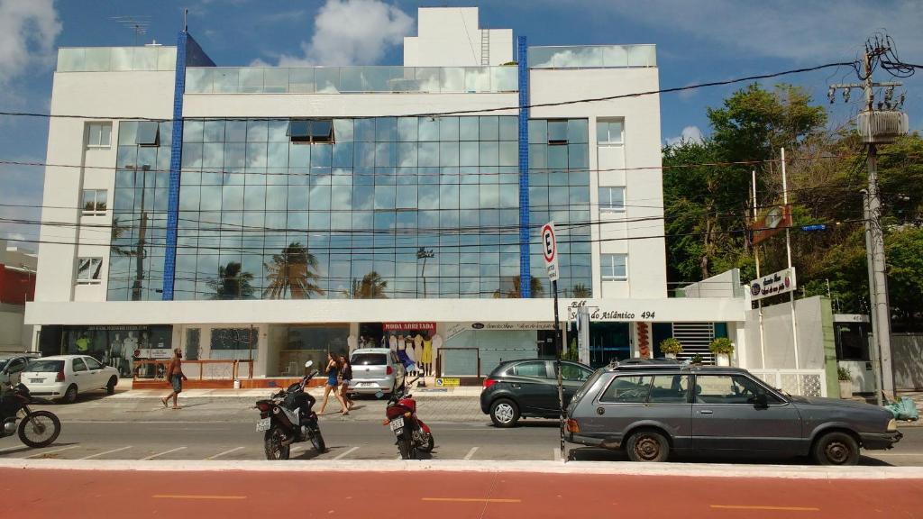 若昂佩索阿Sol e Mar Solar do Atlântico的城市街道上一辆汽车和摩托车的建筑物