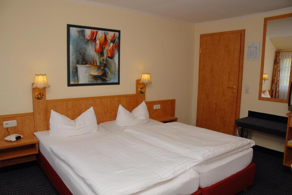 Luhden阿尔特学派酒店的卧室配有一张白色大床,墙上挂有绘画作品
