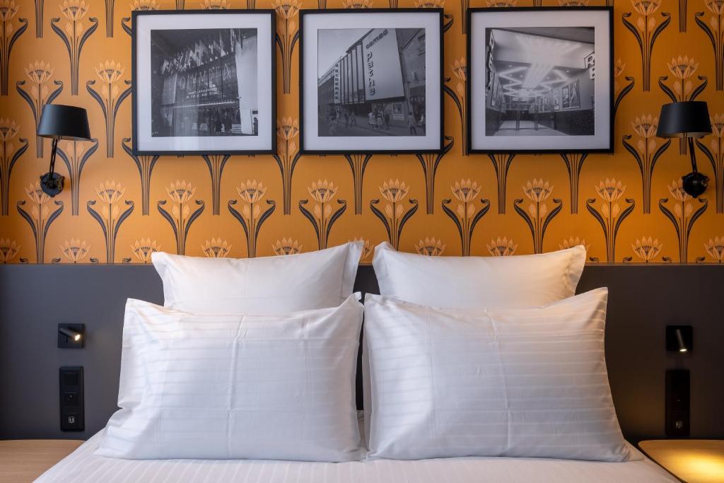 图尔Ferdinand Hotel Tours的卧室配有2个白色枕头和图片墙