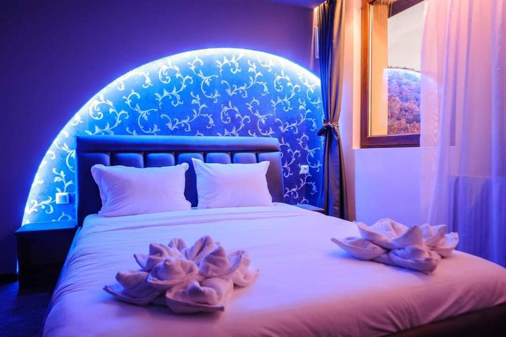 MiladinowziХотел ПИРГУЛЯ的蓝色卧室,床上有两朵鲜花