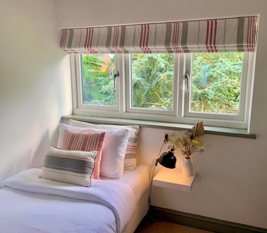 塔滕霍尔The Cottage, Yew Tree Farm Holidays, Tattenhall, Chester的卧室配有带枕头的床铺和窗户。