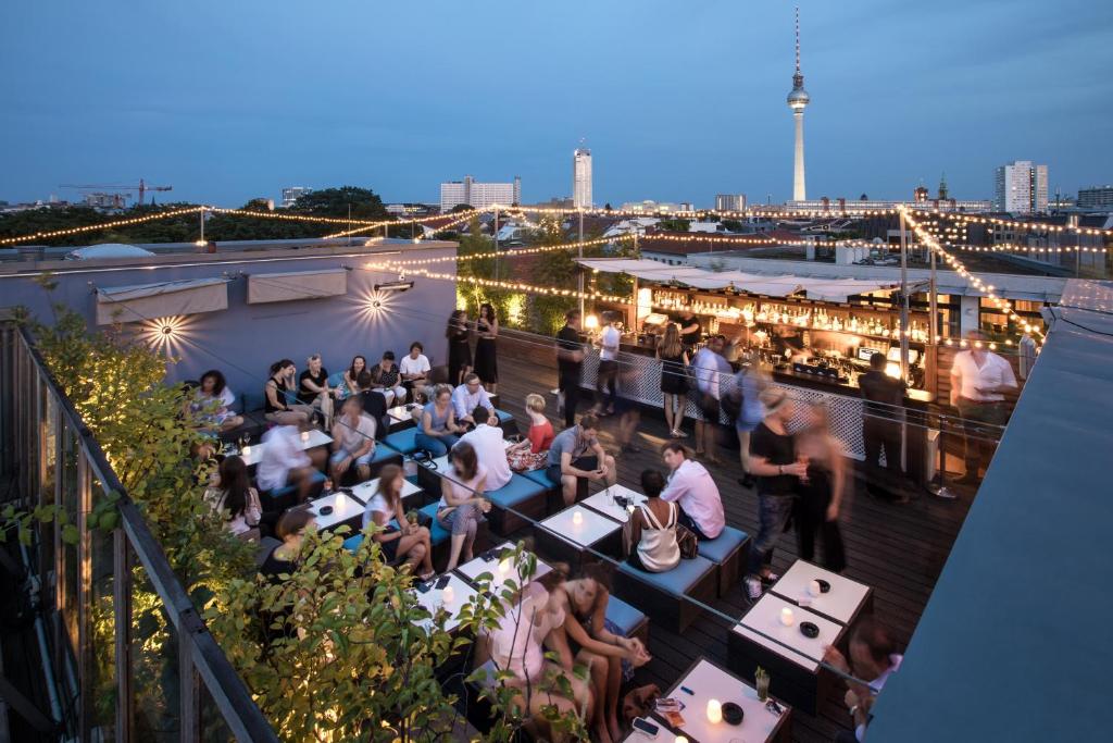 柏林Hotel AMANO Rooms & Apartments的一群人晚上坐在屋顶酒吧