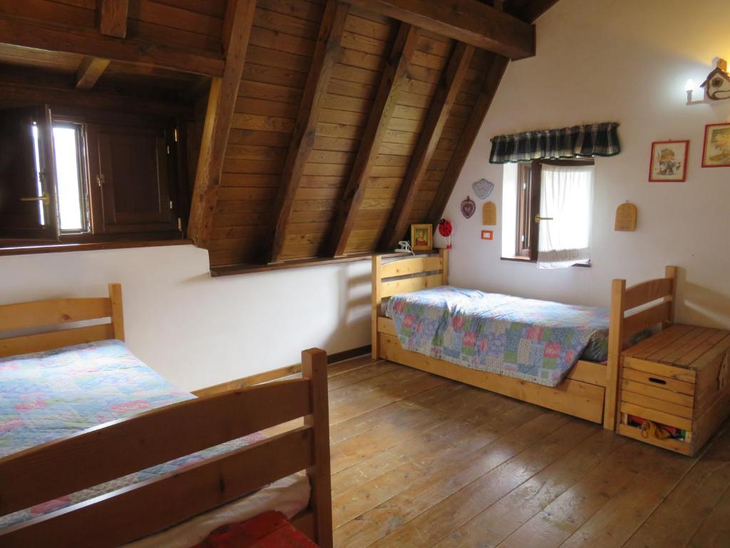 奥温多利tipica baita con vista sul monte magnola的一间卧室设有两张床,铺有木地板。