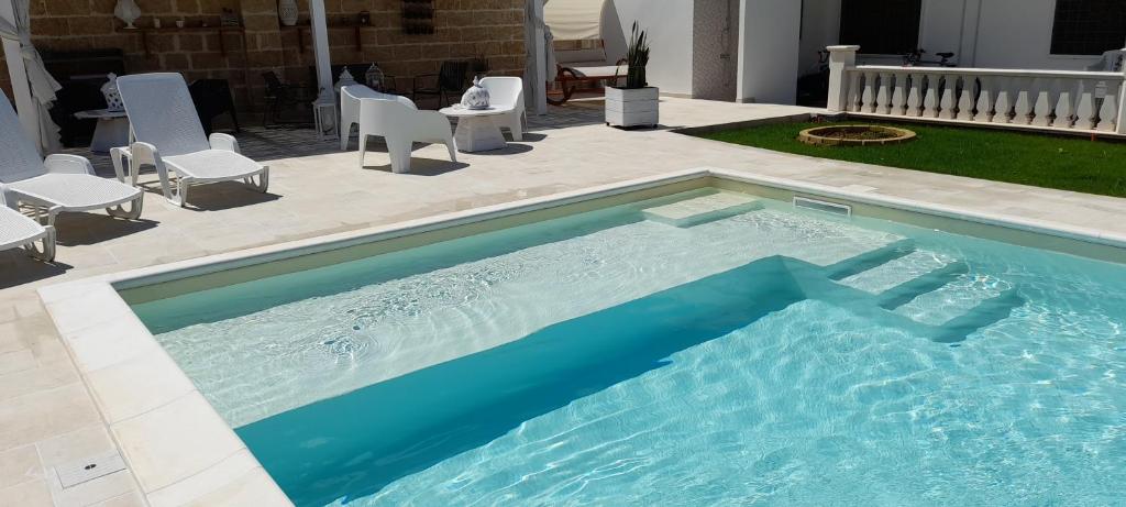 玛丽娜迪曼卡维萨B&B Cinque Stelle Salento的一个带椅子的大型游泳池和一个庭院