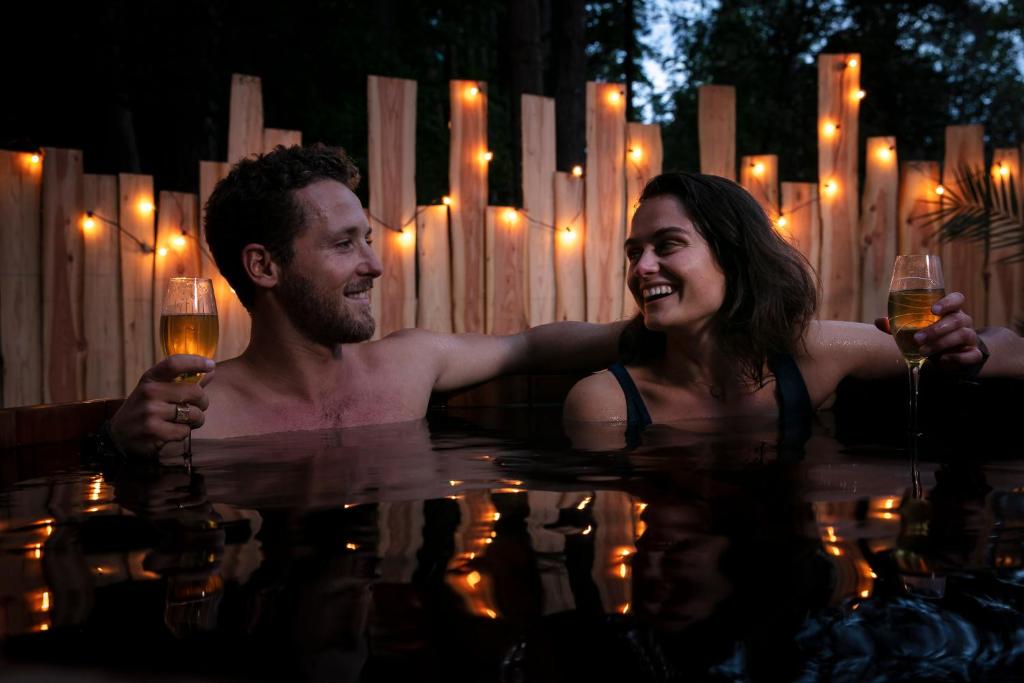 讷沙泰勒阿尔代洛Bain de forêt - Lodges Cosy & Spa的男男女女在游泳池里戴酒杯
