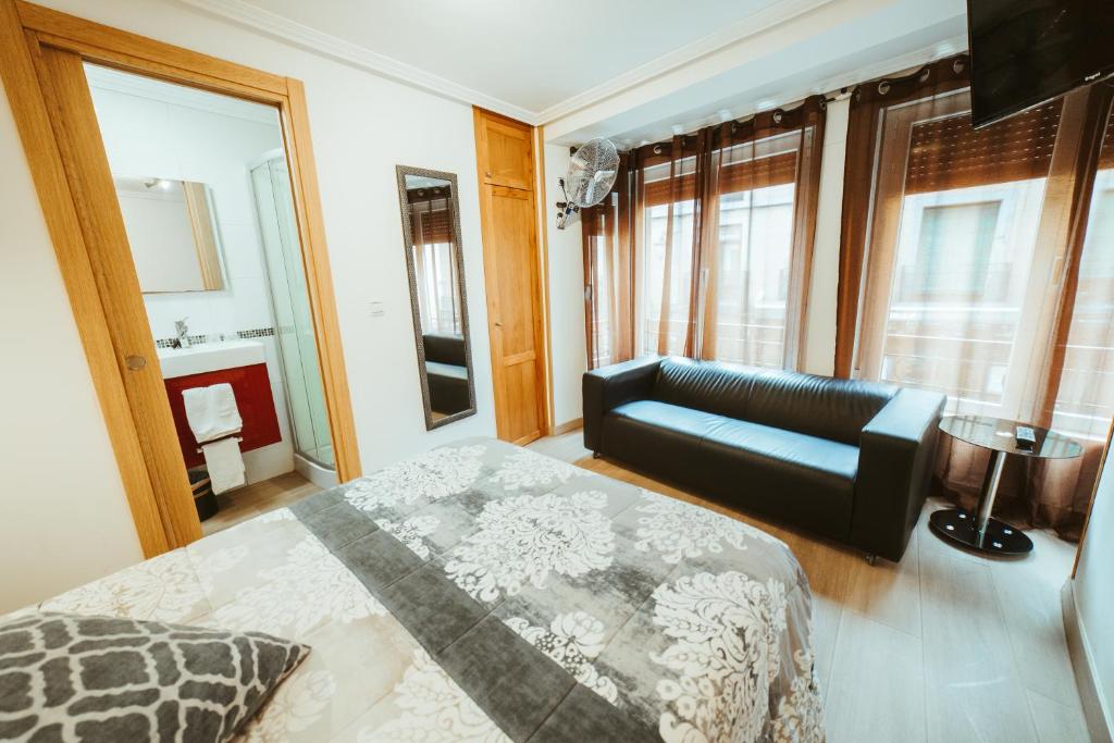 莱昂Hospederia Rincon De Leon的一间卧室配有一张床、一张沙发和窗户。