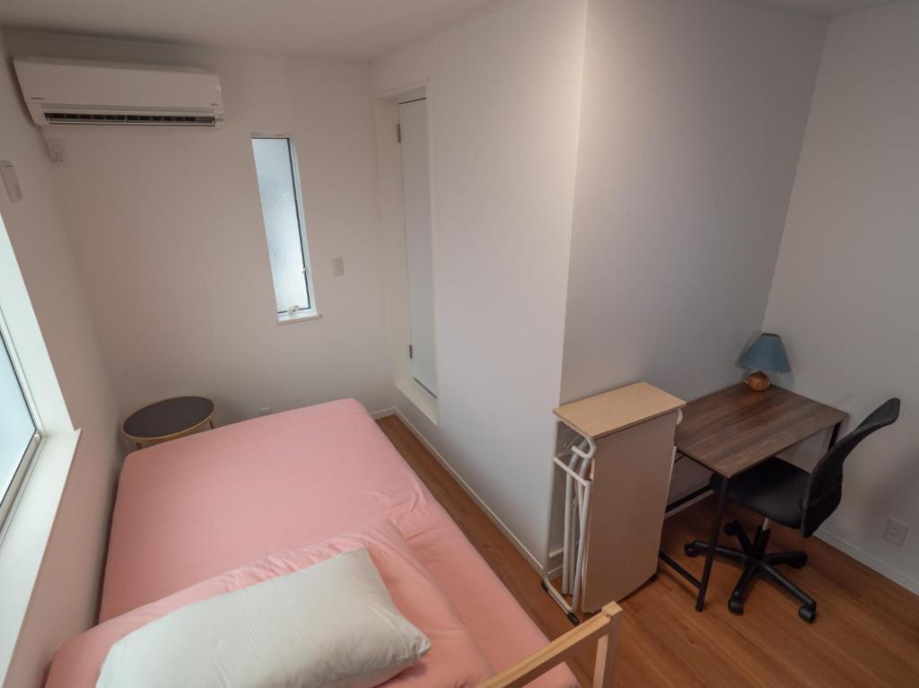 镰仓市Kamakura International House Double Room w Shower Toilette - Vacation STAY 11408的一间小卧室,配有粉红色的床和一张书桌