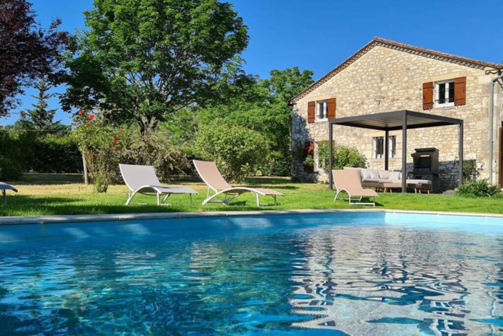 ParranquetGîte de charme piscine privée chauffée climatisé wifi aux portes du Périgord entre Villeréal et Monpazier的一个带椅子的游泳池和一个背景房子