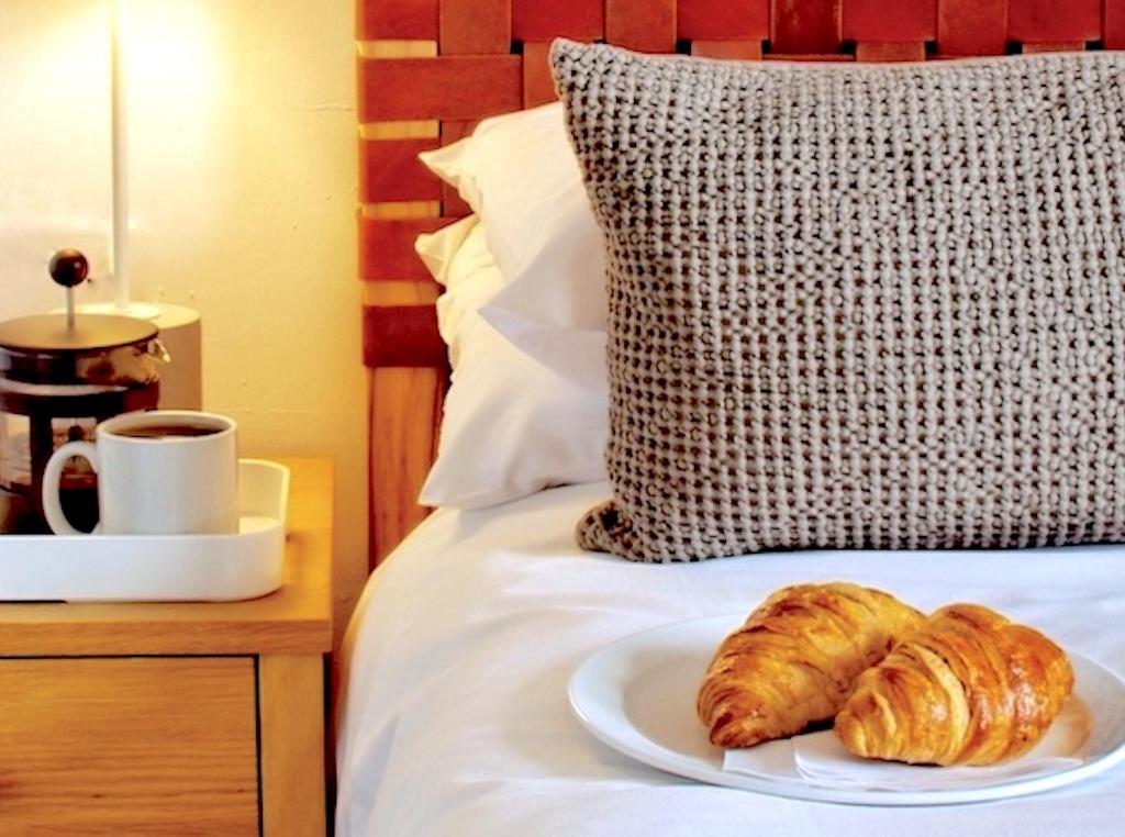 埃克塞特埃克塞特联排别墅旅馆的床上一盘羊角面包和咖啡